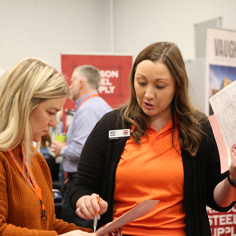 An OSU Career Services staff member speaking with a recruiter on campus.